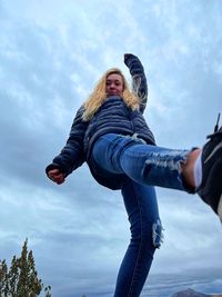 Woman with arms raised against sky during winter