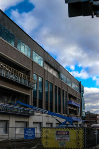 Low angle view of text on building against cloudy sky