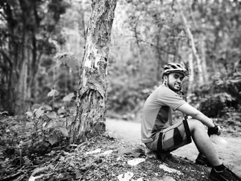 Cyclist looking away while sitting by trees