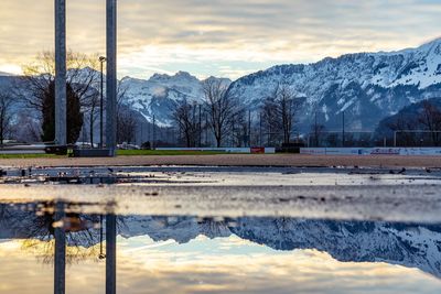 Scenic view of lake by snowcapped mountains against sky during sunset