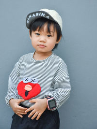 Portrait of cute girl holding jack o lantern against wall