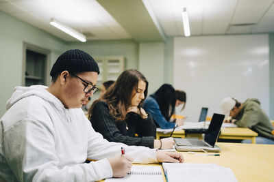 High school students studying at desk in classroom