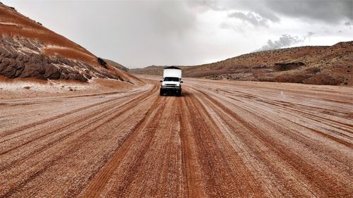 Car on road amidst land against sky