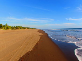 Scenic view of beach against blue sky