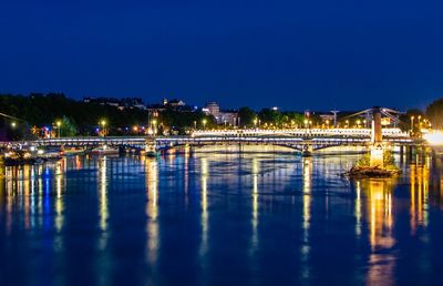 Illuminated bridge over river against sky at night