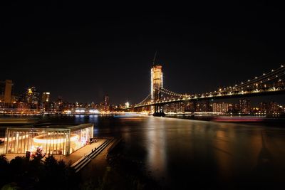 Illuminated bridge over river against sky at night