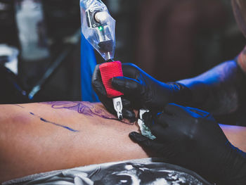 Cropped image of tattooist making tattoo on customer