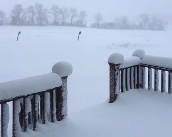Snow covered wooden posts on field during winter