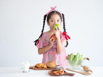 Portrait of smiling girl holding apples against white background