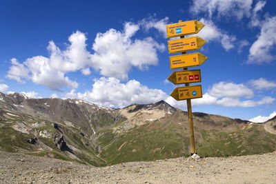 Information sign by road against sky