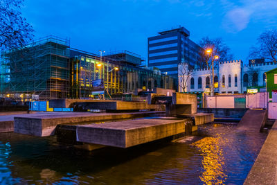 Canal by illuminated city against sky at night