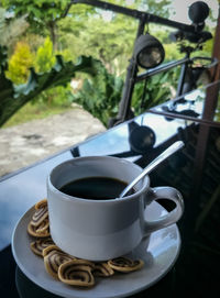 Close-up of coffee cup with biscuits on table