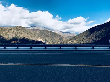 Road by mountains against sky