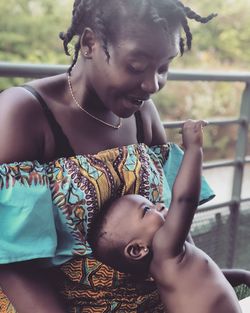 Mother looking at baby girl while sitting by railing