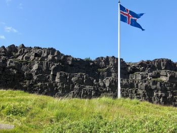 Flag on field by mountain against clear sky