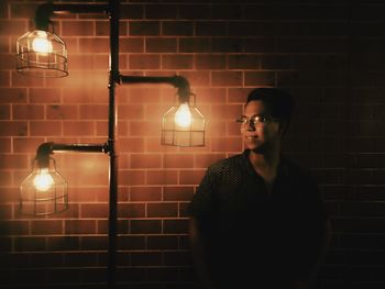 Full length of young man standing against illuminated wall