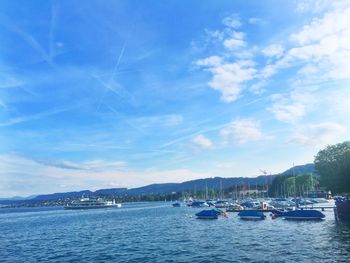 Boats moored on sea against blue sky