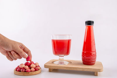 Cropped hand of woman holding drink against white background