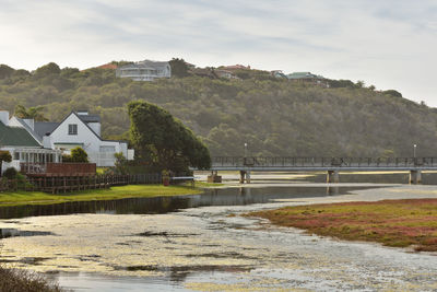 River by houses and buildings against sky