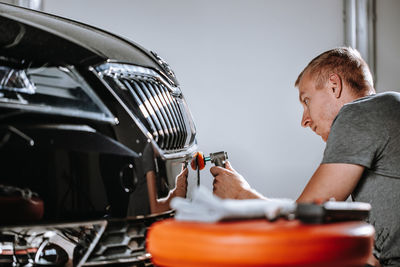 Side view of man repairing car