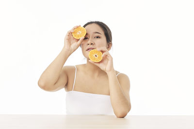 Midsection of woman eating apple against white background