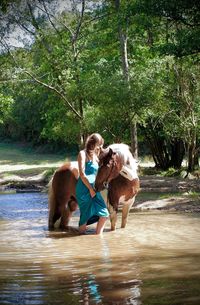 Side view of woman with horse in lake