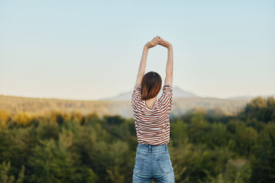 Rear view of woman standing on field against clear sky