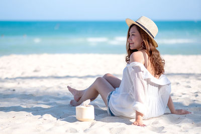 Mid adult woman with coconut enjoying weekend at beach