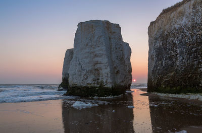 Rock formation on shore at botany bay against sky during sunset