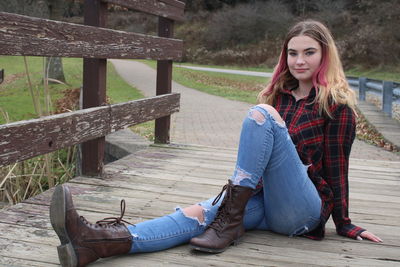 Portrait of young woman sitting on walking bridge