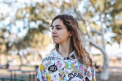 Portrait of beautiful young woman standing against tree