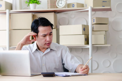 Young man using mobile phone while sitting on table