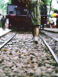 Low section of woman standing on railroad track