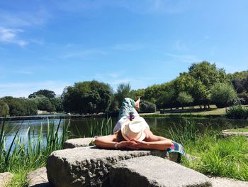 Woman relaxing at lake against sky