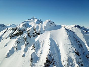 Scenic view of snowcapped mountains against clear blue sky