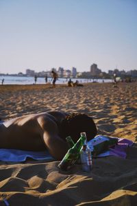 Man relaxing on beach against clear sky