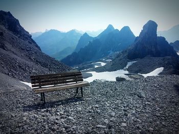 Empty bench against mountains