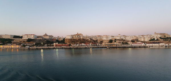 Buildings by river against sky in town