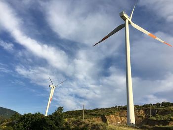 Low angle view of windmill on field against sky