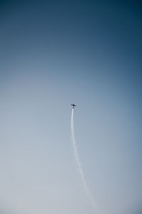 Low angle view of airplane flying against clear blue sky