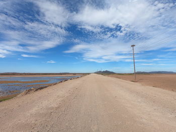 Road leading towards desert against sky