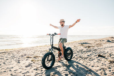 Rear view of man with arms outstretched standing at beach