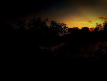 Silhouette trees by lake against sky during sunset