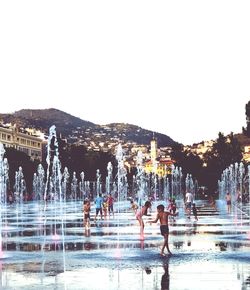 People at swimming pool against clear sky