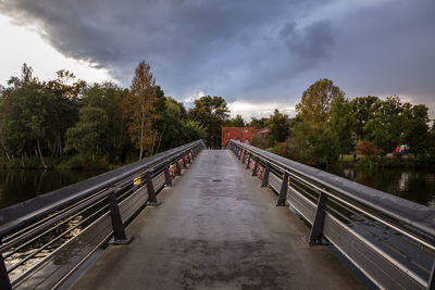 Footbridge amidst trees against sky