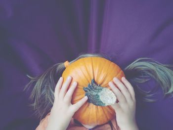 Close-up of girl covering face with pumpkin