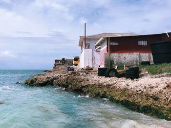 Houses by sea against sky