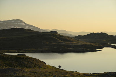 Scenic view of lake by mountains against clear sky