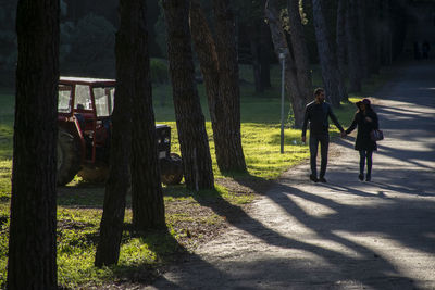 Rear view of people walking on tree trunk