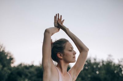 Woman with arms raised against sky